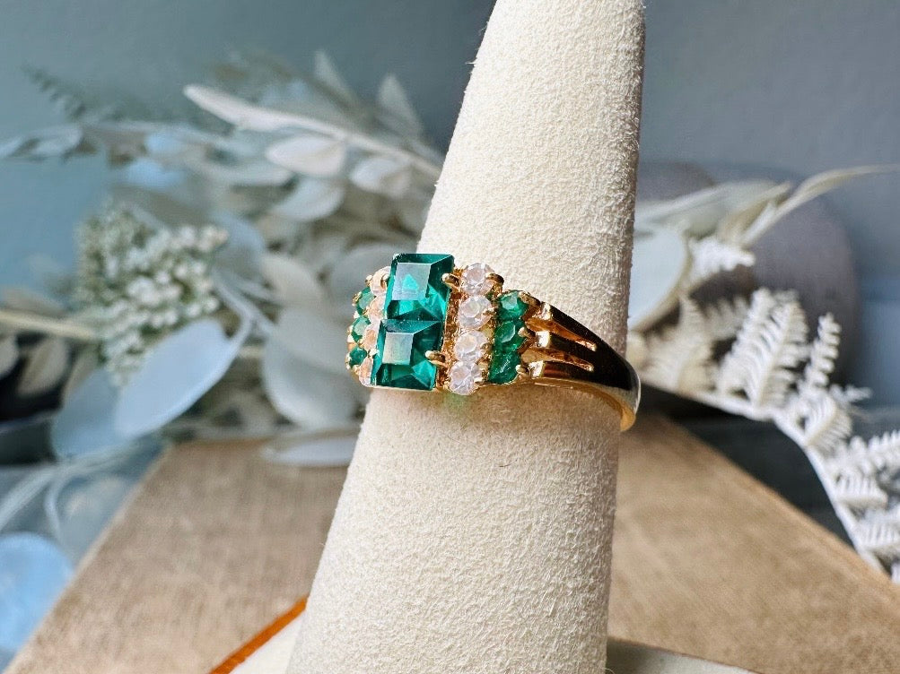 This vintage cocktail ring features a stunning art deco design with brilliant emerald green stacked princess cut rhinestones flanked with dazzling cubic zirconias and tiny green stones. Prong set in a 14K gold-plated base, this fitted size 7 ring is a beautiful and timeless vintage piece. The glass crystals catch the light beautifully and are full of sparkle. This vintage ring will arrive beautifully packaged and ready to gift, or to keep as a treat to yourself.