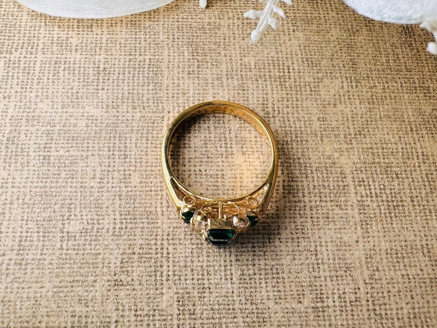 This vintage cocktail ring from Piggle and Pop features a stunning art deco design with brilliant emerald green stacked princess cut rhinestones flanked with dazzling cubic zirconias and tiny green stones. Prong set in a 14K gold-plated base, this fitted size 7 ring is a beautiful and timeless vintage piece. The glass crystals catch the light beautifully and are full of sparkle. This vintage ring will arrive beautifully packaged and ready to gift, or to keep as a treat to yourself.
