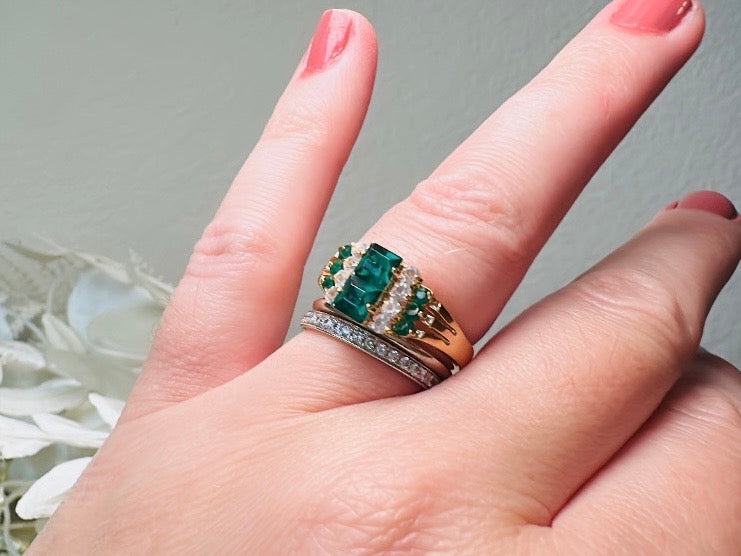 This vintage cocktail ring from Piggle and Pop features a stunning art deco design with brilliant emerald green stacked princess cut rhinestones flanked with dazzling cubic zirconias and tiny green stones. Prong set in a 14K gold-plated base, this fitted size 7 ring is a beautiful and timeless vintage piece. The glass crystals catch the light beautifully and are full of sparkle.