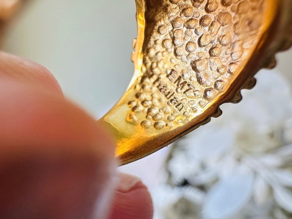 A vintage 1970s cocktail ring, that is gold and purple, The gold band has a raised textured gold nugget surface with a beautiful faceted round cut vibrant amethyst purple in the center. Stamped EM7 Thailand.