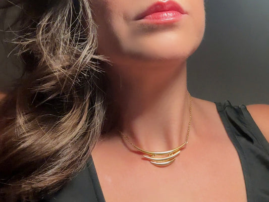 This vintage Crown Trifari triple gold bar necklace is a beauty. From the 1960s this dainty short style choker necklace looks beautiful alone or paired with others for a fantastic stack. The fine gold plated chain suspends a small gold pendant composed of 3 curved bars in graduated size- signed on back and with the signature Trifari hang tag. 