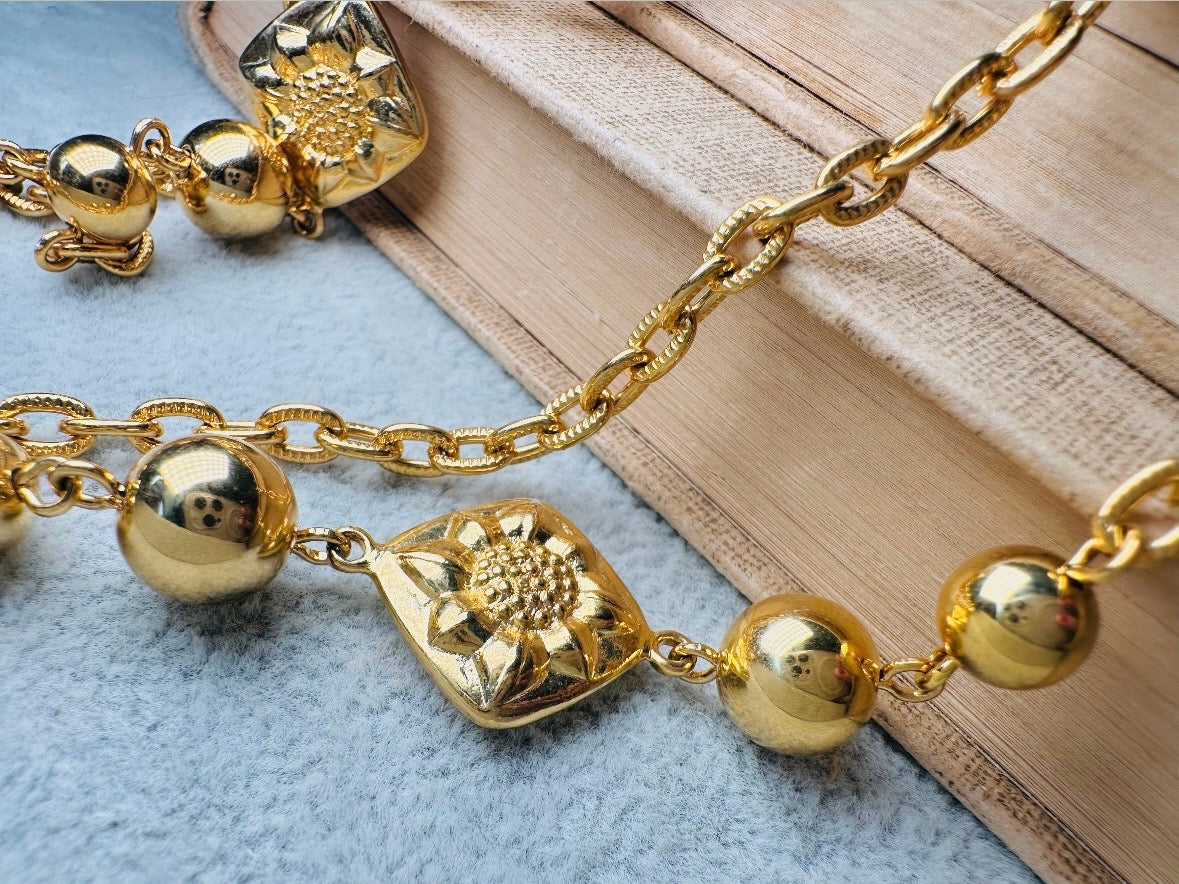This vintage double strand Liz Claiborne gold chain necklace is a beautifully unique find. Featuring two strands of shimmering gold chain already perfectly layered- with graduated gold balls in varying sizes and Etruscan floral accents. Signed with signature LCI triangle hang tag on the end of extender chain. Versatile while making a statement, and incredibly flattering. Excellent vintage condition.