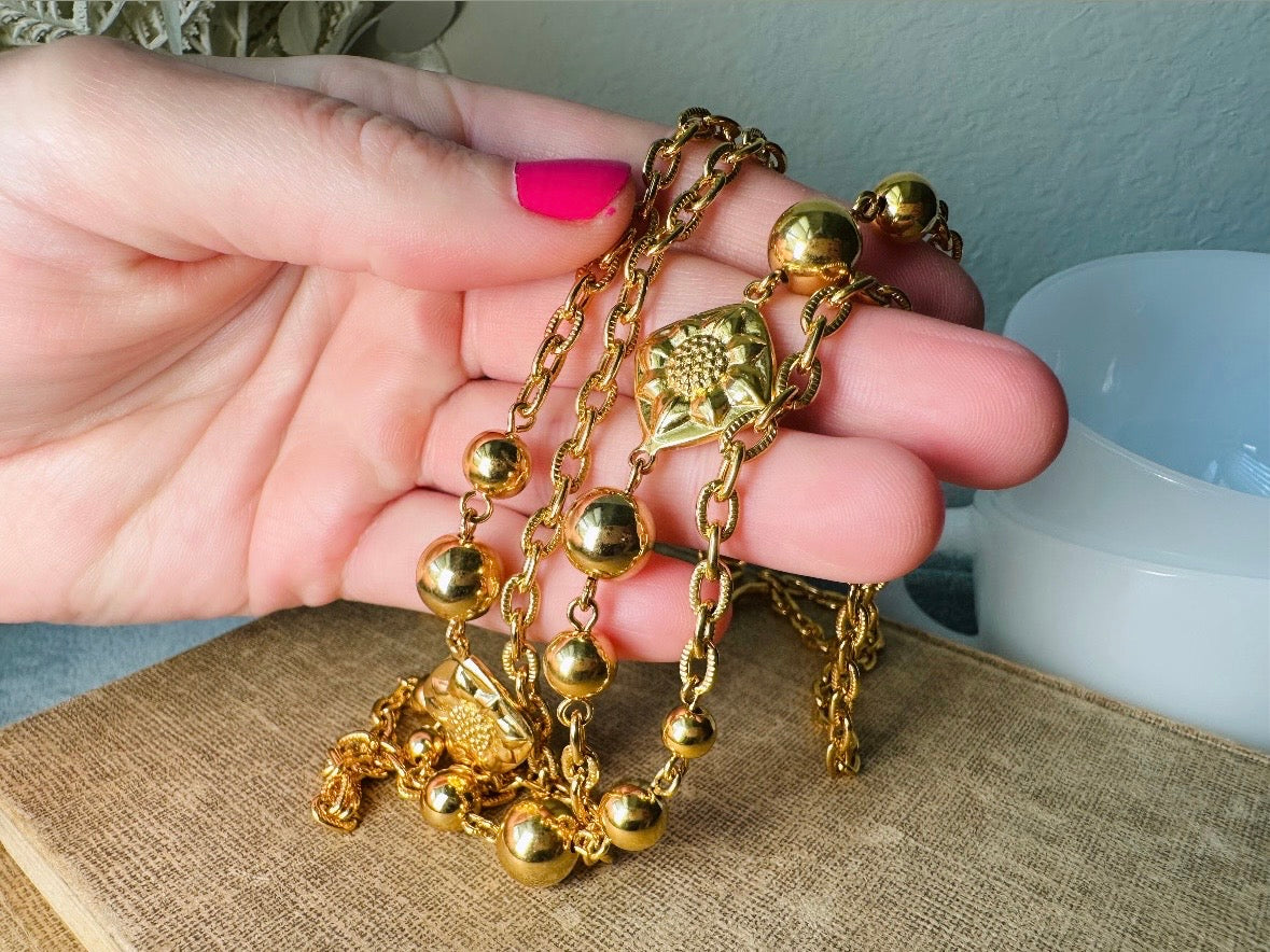 This vintage double strand Liz Claiborne gold chain necklace is a beautifully unique find. Featuring two strands of shimmering gold chain already perfectly layered- with graduated gold balls in varying sizes and Etruscan floral accents. Signed with signature LCI triangle hang tag on the end of extender chain. Versatile while making a statement, and incredibly flattering. Excellent vintage condition.