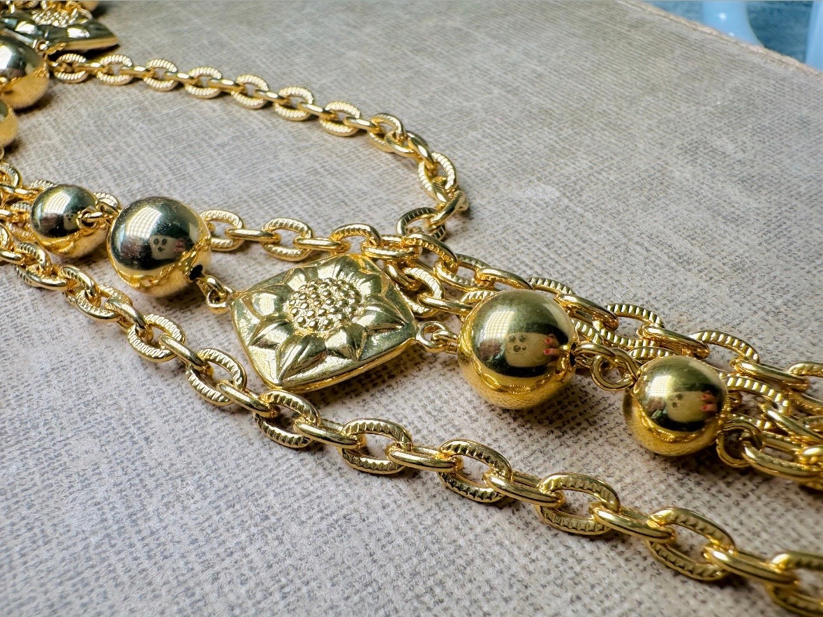 This vintage double strand Liz Claiborne gold chain necklace is a beautifully unique find. Featuring two strands of shimmering gold chain already perfectly layered- with graduated gold balls in varying sizes and Etruscan floral accents. Signed with signature LCI triangle hang tag on the end of extender chain. Versatile while making a statement, and incredibly flattering. Excellent vintage condition.