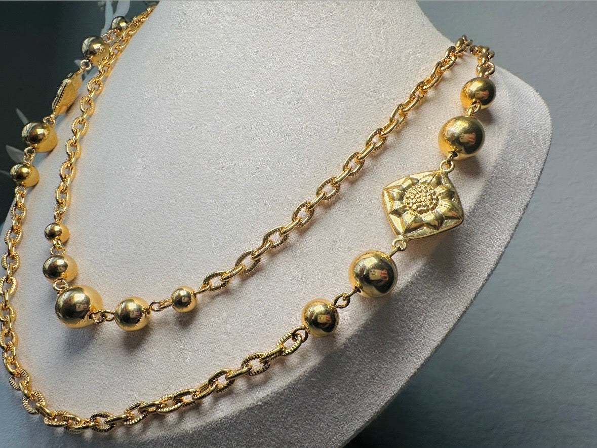 This vintage double strand Liz Claiborne gold chain necklace is a beautifully unique find. Featuring two strands of shimmering gold chain already perfectly layered- with graduated gold balls in varying sizes and Etruscan floral accents. Signed with signature LCI triangle hang tag on the end of extender chain. Versatile while making a statement, and incredibly flattering. Excellent vintage condition.
