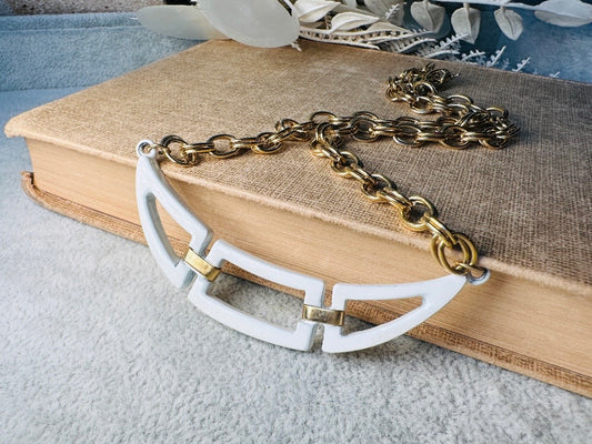 This white and gold vintage geometric necklace is chic and unique. Double link gold curb chain connects with a white geometric pendant bib, comprised or three white enameled articulated pieces. Versatile while making a statement. Minimal wear and in great vintage condition. A perfect summer necklace to incorporate into a variety of looks, paired with others or worn alone.

Dimensions:  18" long
