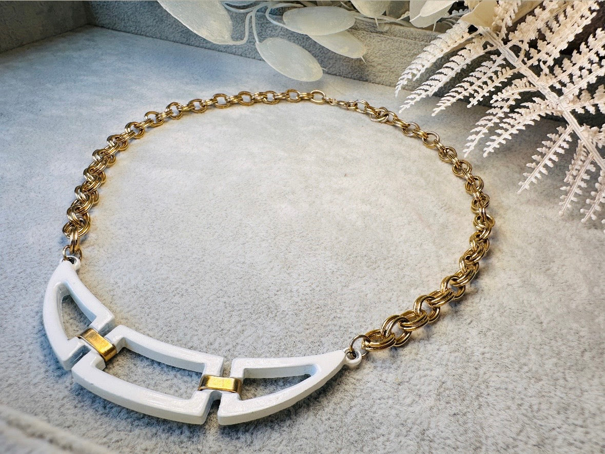 This white and gold vintage geometric necklace is chic and unique. Double link gold curb chain connects with a white geometric pendant bib, comprised or three white enameled articulated pieces. Versatile while making a statement. Minimal wear and in great vintage condition. A perfect summer necklace to incorporate into a variety of looks, paired with others or worn alone.

Dimensions:  18" long