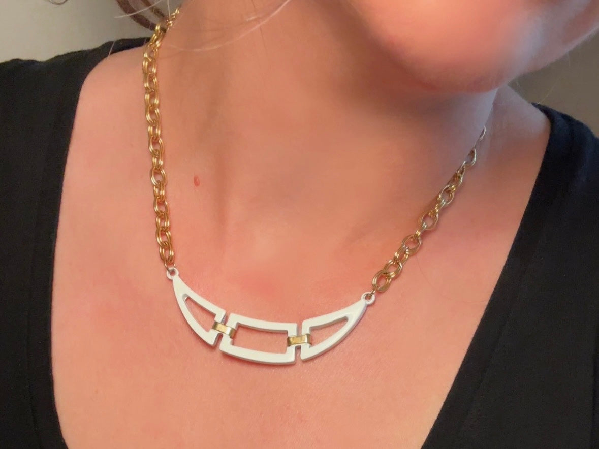 This white and gold vintage geometric necklace is chic and unique. Double link gold curb chain connects with a white geometric pendant bib, comprised or three white enameled articulated pieces. Versatile while making a statement. Minimal wear and in great vintage condition. A perfect summer necklace to incorporate into a variety of looks, paired with others or worn alone.

Dimensions:  18" long