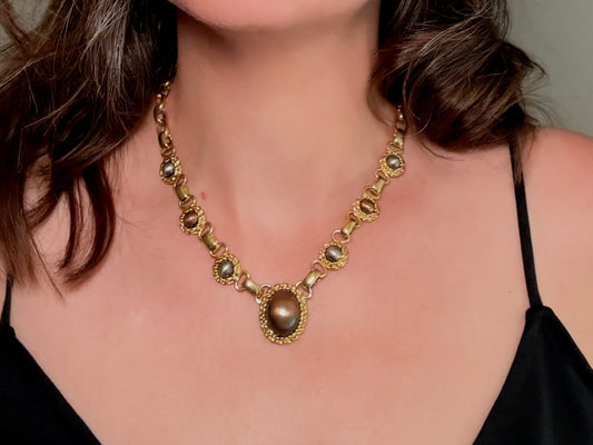 This vintage Etruscan style Liz Claiborne gold chain necklace is a beautifully unique find. Featuring large curb chain links with round cabochons of faux hematite and bronze set in gold bezels. In the center is a larger bronzed oval cabochon in the same style of gold roped bezel. Signed on back of center cabochon as well as the signature LCI triangle hang tag on the end of extender chain. Versatile while making a statement, and incredibly flattering. Minimal wear from age, no major flaws to note; &nbsp;in g