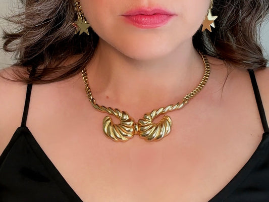 This 1970s vintage gold necklace is such a striking and unique piece. Featuring gold curb chain and a striking centerpiece of two textured gold horns. Full of vintage flair, this centerpiece is dimensional and stunning. This choker necklace is so flattering on and the perfect collar length. An excellent gift for the vintage lover in your life (especially if that's you!).
