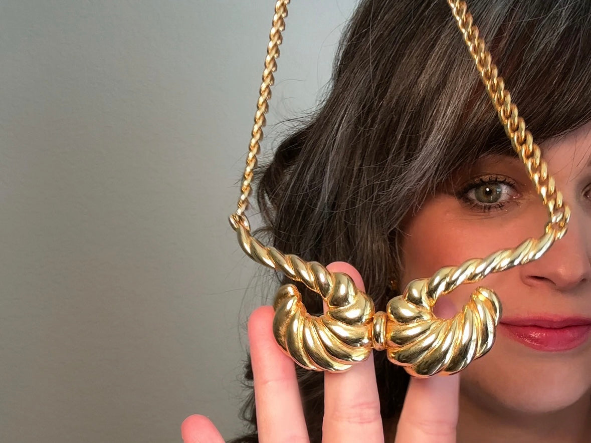 This 1970s vintage gold necklace is such a striking and unique piece. Featuring gold curb chain and a striking centerpiece of two textured gold horns. Full of vintage flair, this centerpiece is dimensional and stunning. This choker necklace is so flattering on and the perfect collar length. 