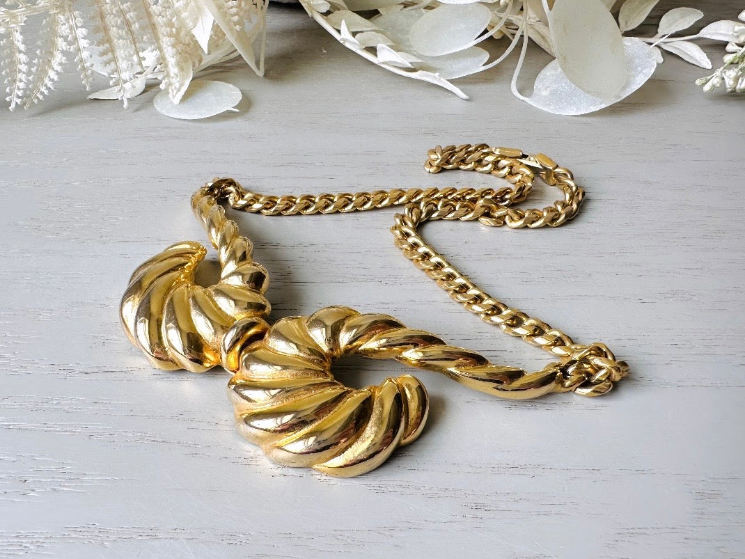 This 1970s vintage gold necklace is such a striking and unique piece. Featuring gold curb chain and a striking centerpiece of two textured gold horns. Full of vintage flair, this centerpiece is dimensional and stunning. This choker necklace is so flattering on and the perfect collar length. 