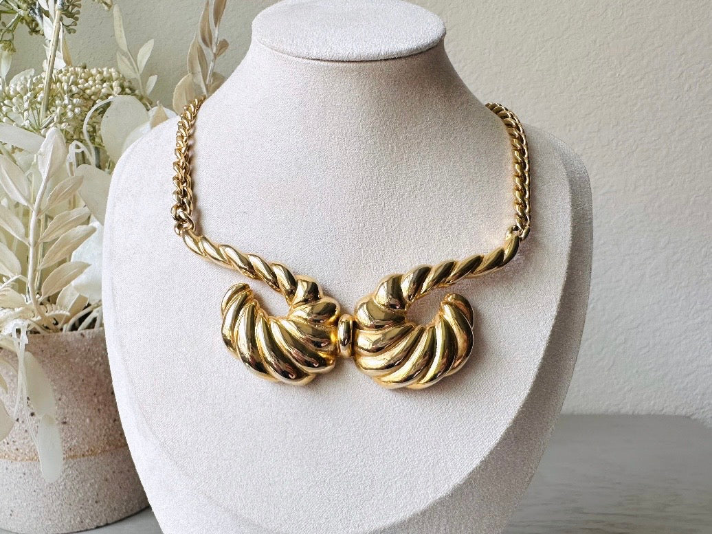 This 1970s vintage gold necklace is such a striking and unique piece. Featuring gold curb chain and a striking centerpiece of two textured gold horns. Full of vintage flair, this centerpiece is dimensional and stunning. This choker necklace is so flattering on and the perfect collar length. 