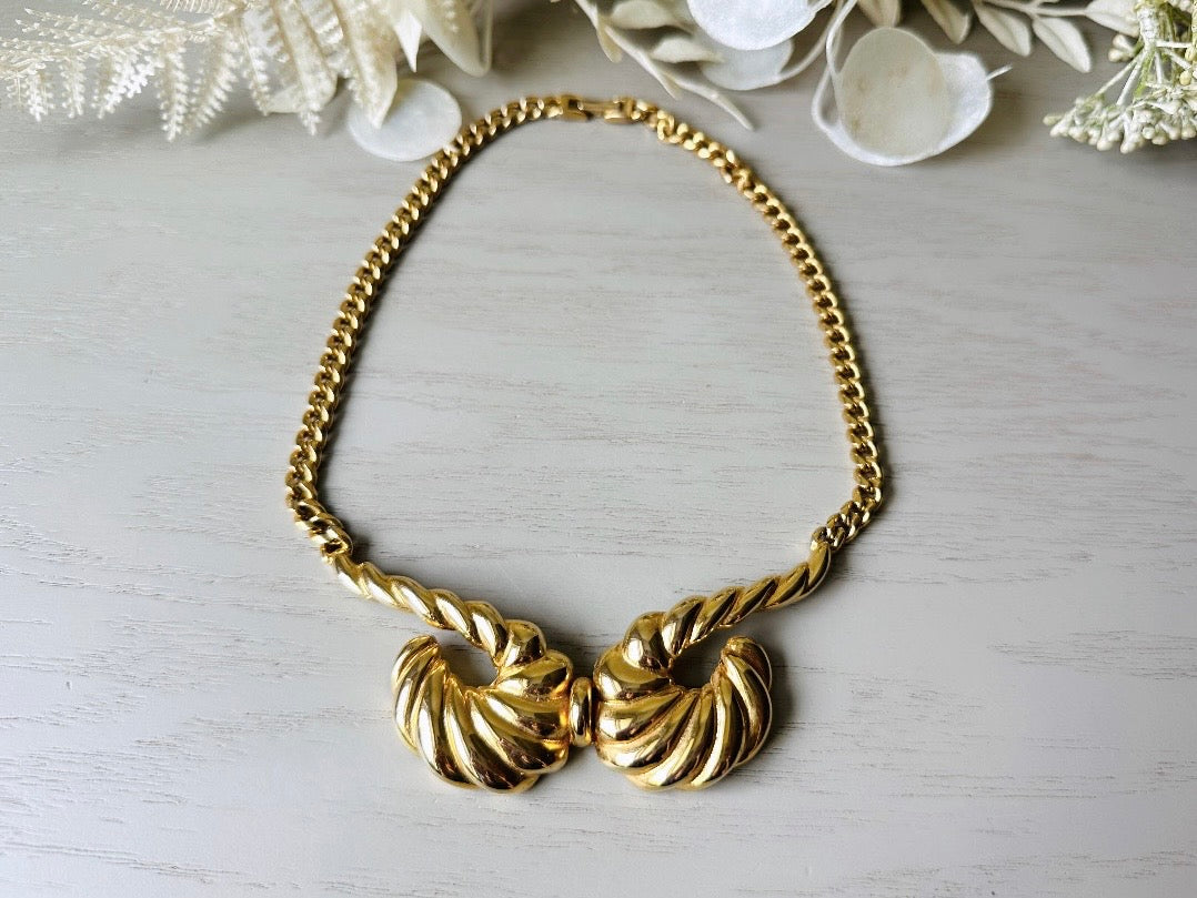 This 1970s vintage gold necklace is such a striking and unique piece. Featuring gold curb chain and a striking centerpiece of two textured gold horns. Full of vintage flair, this centerpiece is dimensional and stunning. This choker necklace is so flattering on and the perfect collar length. 