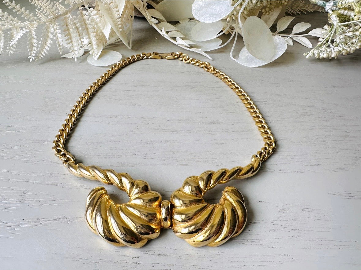 This 1970s vintage gold necklace is such a striking and unique piece. Featuring gold curb chain and a striking centerpiece of two textured gold horns. Full of vintage flair, this centerpiece is dimensional and stunning. This choker necklace is so flattering on and the perfect collar length. 