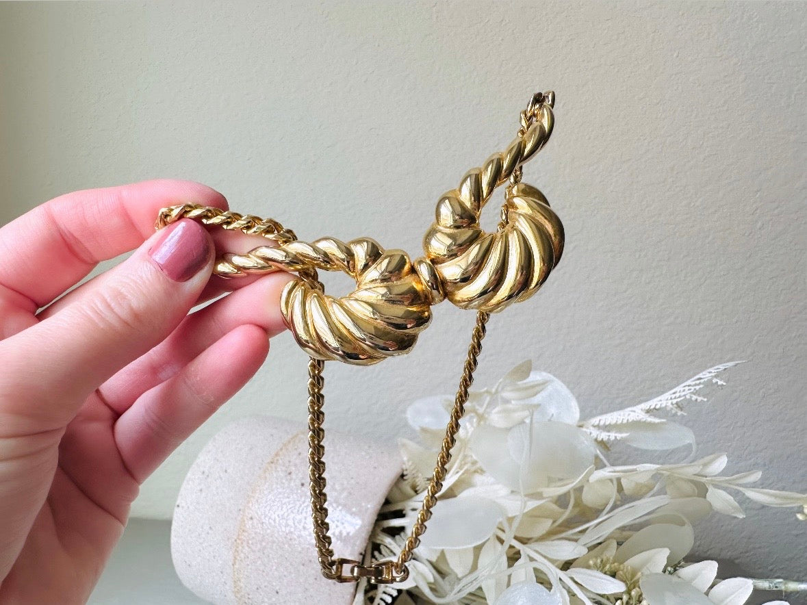 This 1970s vintage gold necklace is such a striking and unique piece. Featuring gold curb chain and a striking centerpiece of two textured gold horns. Full of vintage flair, this centerpiece is dimensional and stunning. This choker necklace is so flattering on and the perfect collar length. 