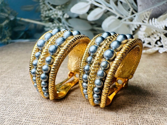 These oversized gold hoop vintage statement earrings feature two rows of chanel set dark silver pearls in graduating size, the sides are a beautiful roped texture. These dark silver pearl and gold half hoop earrings are huggie hoop style- these clip ons effortlessly add a touch of bold glam the 80s are so beloved for. A beautiful textured finish, the contrast of cool silver pearls and classic gold- these earrings are a showstopping vintage pair, in excellent condition.