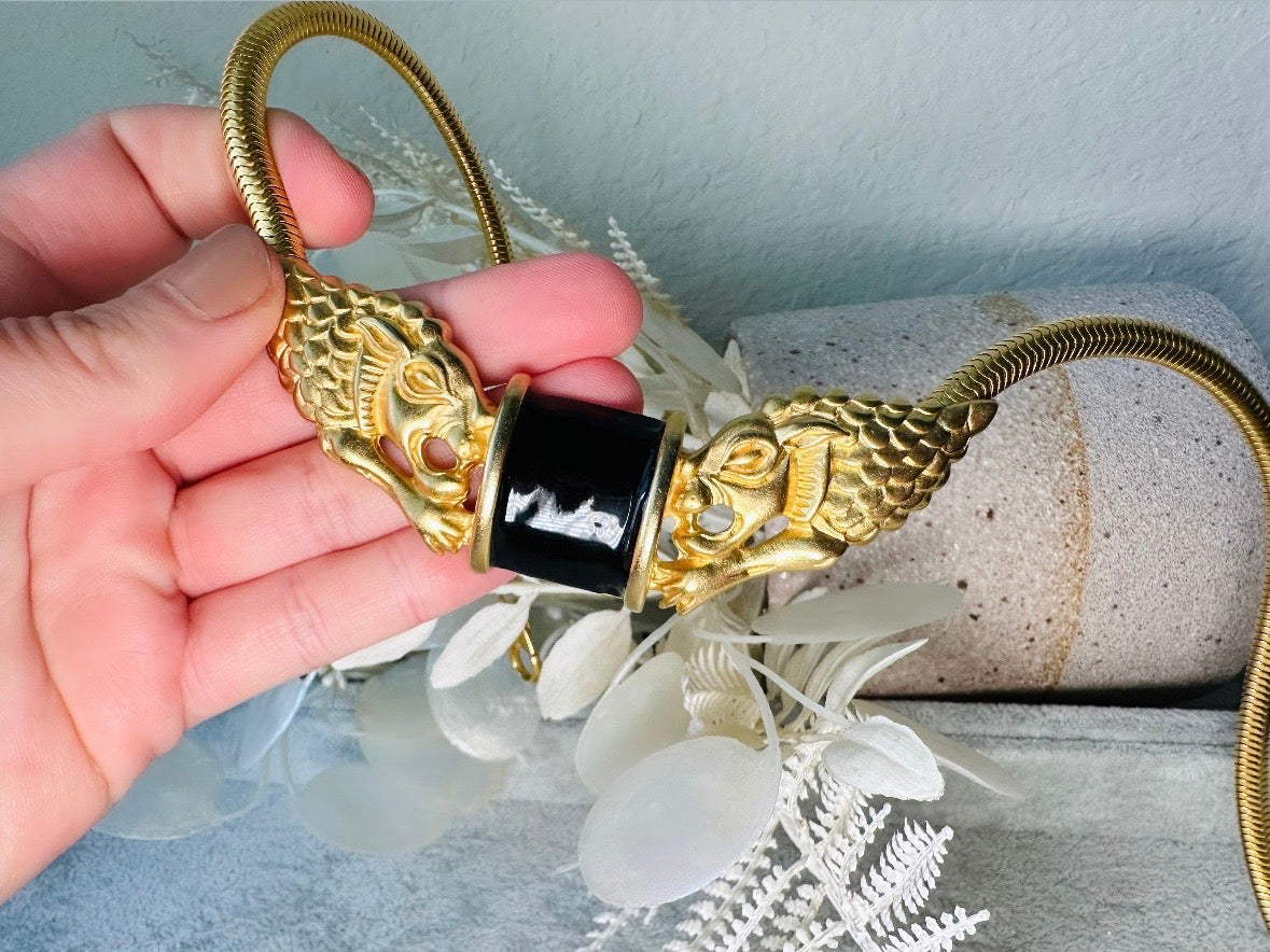 This bold vintage Etruscan style double lion necklace is truly incredible. Featuring two intricate sculptural gold lions on either side of a black enamel focal. This vintage collar necklace is the height of 80s glam, with its contrasting shiny black enamel and matte satin gold components. Wide snake chain and an oversized clasp complete this sensational necklace. 