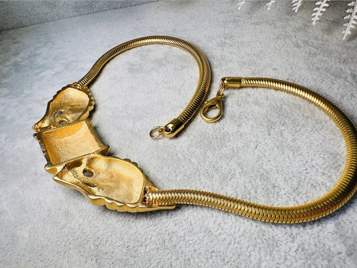 This bold vintage Etruscan style double lion necklace is truly incredible. Featuring two intricate sculptural gold lions on either side of a black enamel focal. This vintage collar necklace is the height of 80s glam, with its contrasting shiny black enamel and matte satin gold components. Wide snake chain and an oversized clasp complete this sensational necklace. 