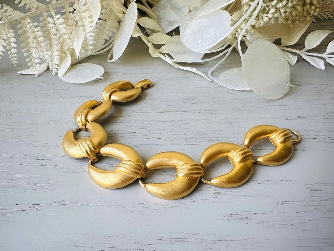 This is a matte gold chain link vintage bracelet by Premier Designs. The links are round and wide with textured ribbing in the center. The finish is a satin matte gold. Very popular style in the 1980s and modern.