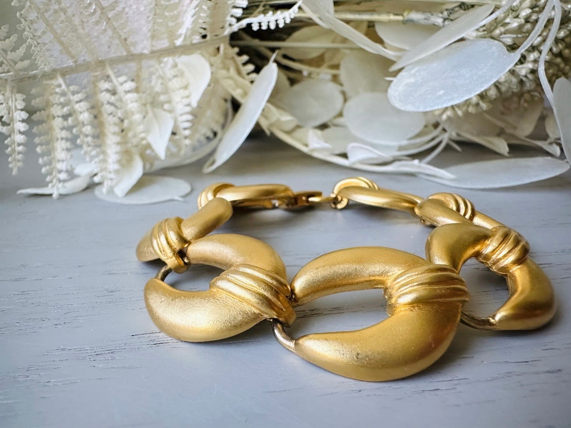 This is a matte gold chain link vintage bracelet by Premier Designs. The links are round and wide with textured ribbing in the center. The finish is a satin matte gold. Very popular style in the 1980s and modern.
