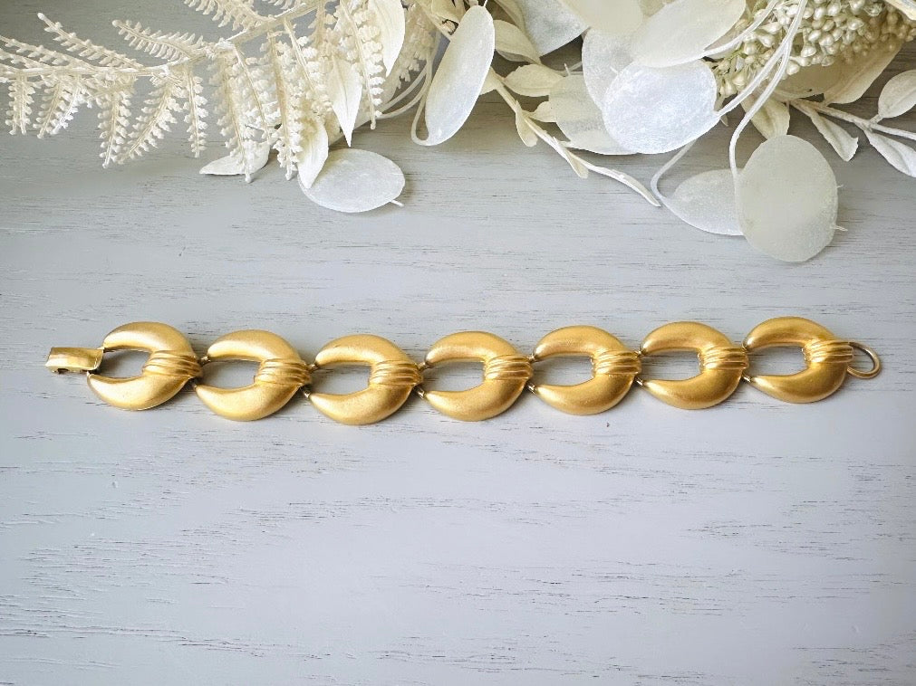 This is a matte gold chain link vintage bracelet by Premier Designs. The links are round and wide with textured ribbing in the center. The finish is a satin matte gold. Very popular style in the 1980s and modern.
