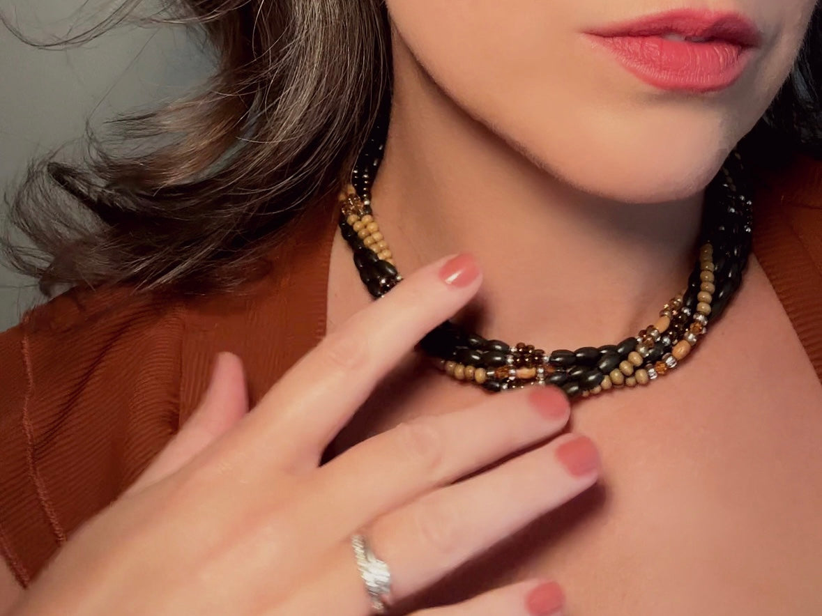 This vintage Napier necklace is a beautiful beaded twisted multistrand choker. Featuring six beaded strands in varying shapes and sizes composed of beads in wood, glass, acrylic, this bold necklace is a fabulous addition to your jewelry box. The beaded strands connect with a gold extension chain finished with a beautiful stamped Napier tag. 
