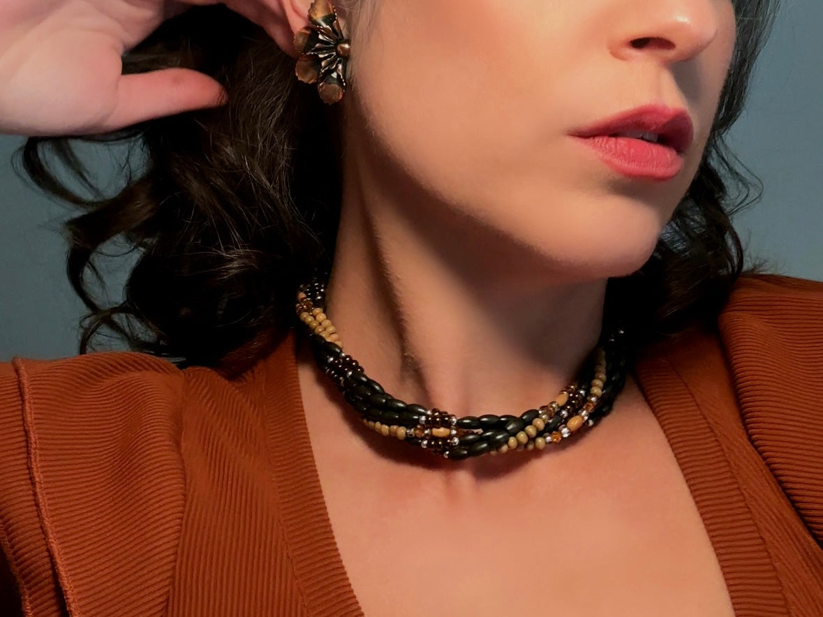This vintage Napier necklace is a beautiful beaded twisted multistrand choker. Featuring six beaded strands in varying shapes and sizes composed of beads in wood, glass, acrylic, this bold necklace is a fabulous addition to your jewelry box. The beaded strands connect with a gold extension chain finished with a beautiful stamped Napier tag. 
