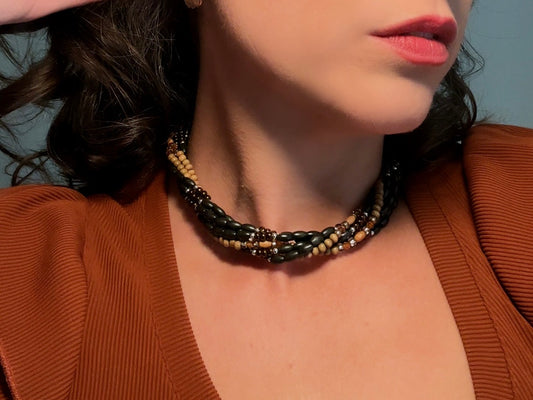This vintage Napier necklace is a beautiful beaded twisted multistrand choker. Featuring six beaded strands in varying shapes and sizes composed of beads in wood, glass, acrylic, this bold necklace is a fabulous addition to your jewelry box. The beaded strands connect with a gold extension chain finished with a beautiful stamped Napier tag. 