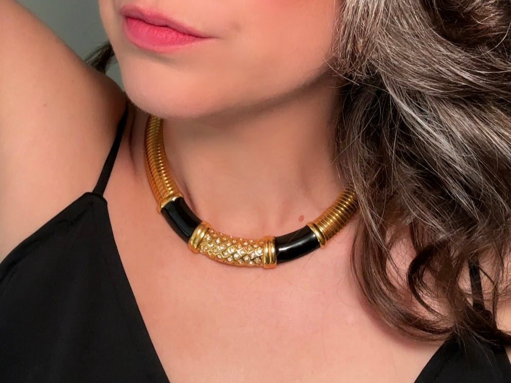 This vintage omega necklace is a stunning black and gold Monet designer vintage necklace. Featuring wide band snake chain and geometric segments of black enamel. This 1980s vintage rhinestone collar necklace has a fold over clasp and extender link. &nbsp;Excellent condition. This vintage designer necklace is high quality, weighty and well made. Modeled for size reference.