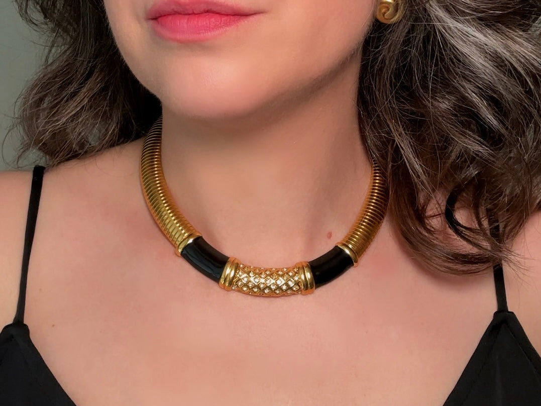 This vintage omega necklace is a stunning black and gold Monet designer vintage necklace. Featuring wide band snake chain and geometric segments of black enamel. This 1980s vintage rhinestone collar necklace has a fold over clasp and extender link. &nbsp;Excellent condition. This vintage designer necklace is high quality, weighty and well made. 