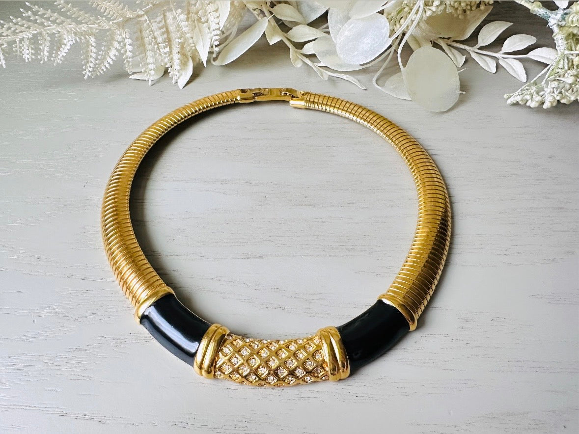 This vintage omega necklace is a stunning black and gold Monet designer vintage necklace. Featuring wide band snake chain and geometric segments of black enamel. This 1980s vintage rhinestone collar necklace has a fold over clasp and extender link. &nbsp;Excellent condition. This vintage designer necklace is high quality, weighty and well made. 