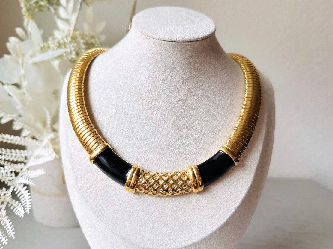 This vintage omega necklace is a stunning black and gold Monet designer vintage necklace. Featuring wide band snake chain and geometric segments of black enamel. This 1980s vintage rhinestone collar necklace has a fold over clasp and extender link. &nbsp;Excellent condition. This vintage designer necklace is high quality, weighty and well made. 