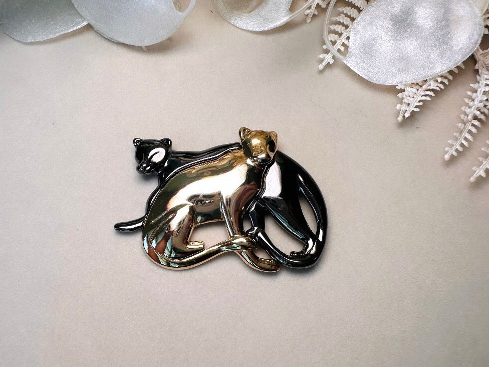 Metallic brooch with two panthers on a light background