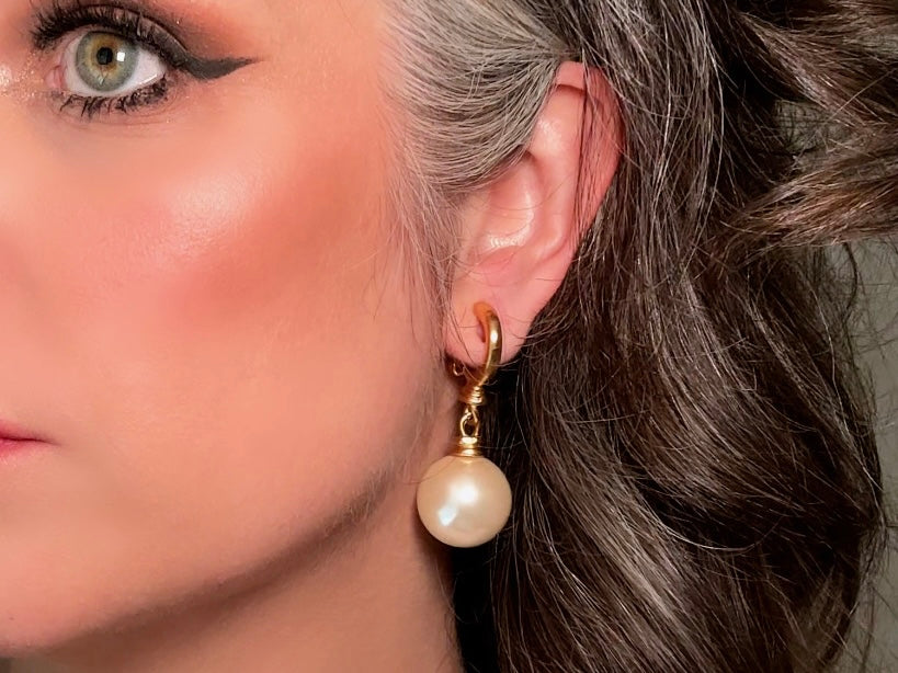 These vintage matte gold and cream pearl drop earrings are clip ons, shown on a model. They are very elegant. They give the appearance of half huggie hoops in a beautiful satin matte finish gold, with a striking oversized cream glass pearl. These Etruscan statement drop earrings are very on trend. These earrings are 2 inches long, unsigned in excellent condition.
