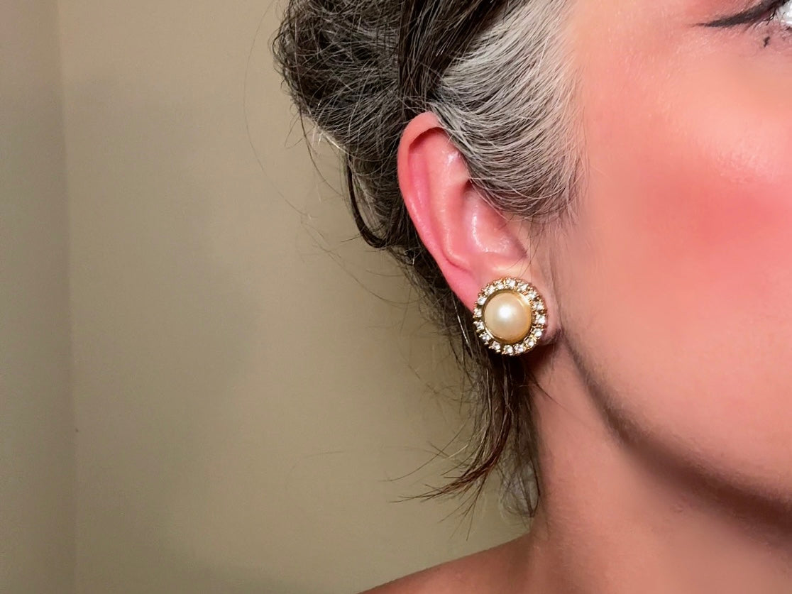 These gold and cream pearl button earrings are a classic old money aesthetic pair from the 80s. Featuring a beautiful cream faux pearl cabochon surrounded by a prong set rhinestone border. These clip on earrings are both unique and a timeless classic, old Hollywood glam style in great vintage condition. 

Dimensions: about 1", please view all pics for a visual size reference.
