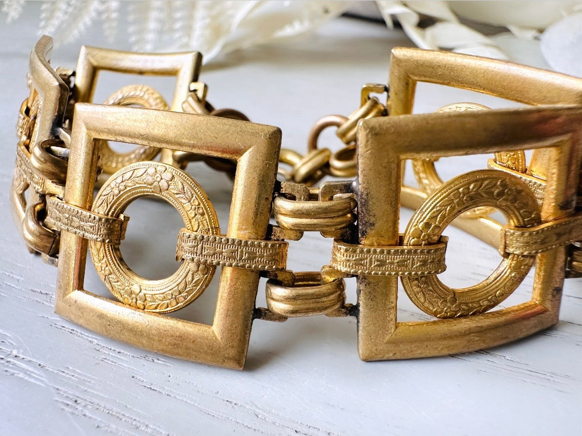 This is a vintage square link bracelet composed of antique gold geometric links. Featuring five structured squares with a floral embossed circle ring inside each one. This bold 1970s vintage chain bracelet is so unique; the circle inside of square and contrast of the bold shape with the royal floral motif is so interesting. It is 7 inches long in great vintage condition.