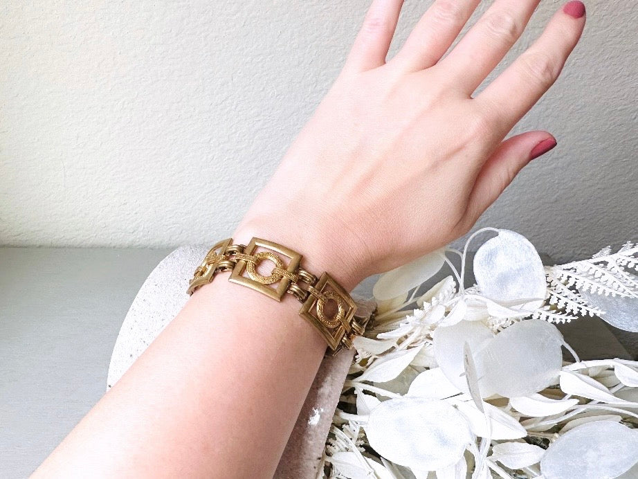 This is a vintage square link bracelet composed of antique gold geometric links. Featuring five structured squares with a floral embossed circle ring inside each one. This bold 1970s vintage chain bracelet is so unique; the circle inside of square and contrast of the bold shape with the royal floral motif is so interesting. It is 7 inches long in great vintage condition. worn on wrist for size reference.