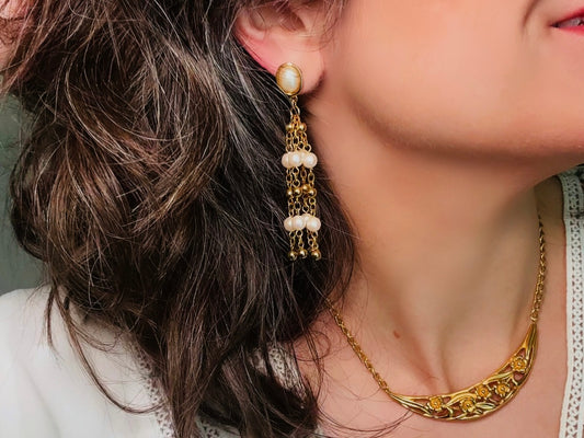 A pair of elegant vintage Trifari pearl chandelier earrings from the 1980s. These signed Trifari designer vintage earrings feature a cream pearl oval framed in gold as the post with a cascade of delicate long fine gold chain tassels with pearl links. In excellent vintage condition, they are three inches long.