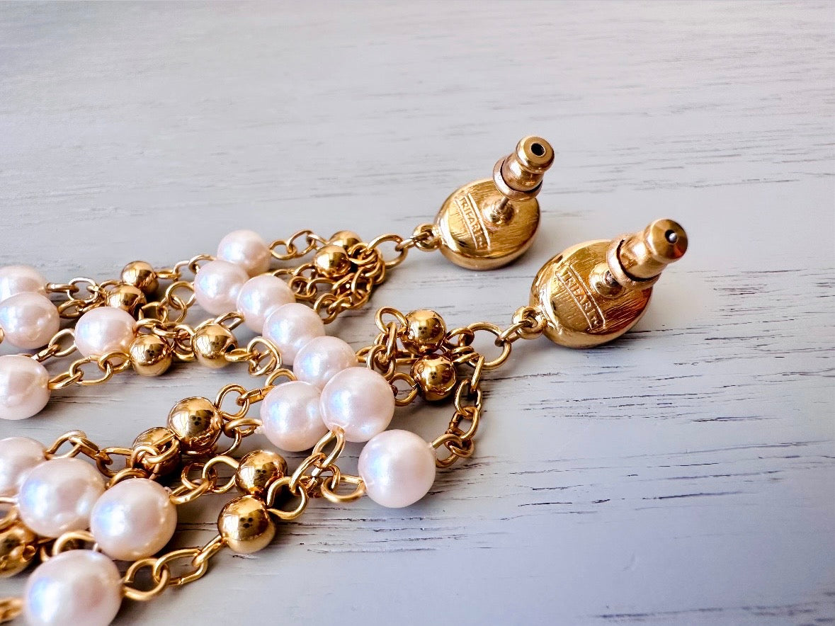 A pair of elegant vintage Trifari pearl chandelier earrings from the 1980s. These signed Trifari designer vintage earrings feature a cream pearl oval framed in gold as the post with a cascade of delicate long fine gold chain tassels with pearl links. In excellent vintage condition, they are three inches long. showing the signature Trifari stamp.