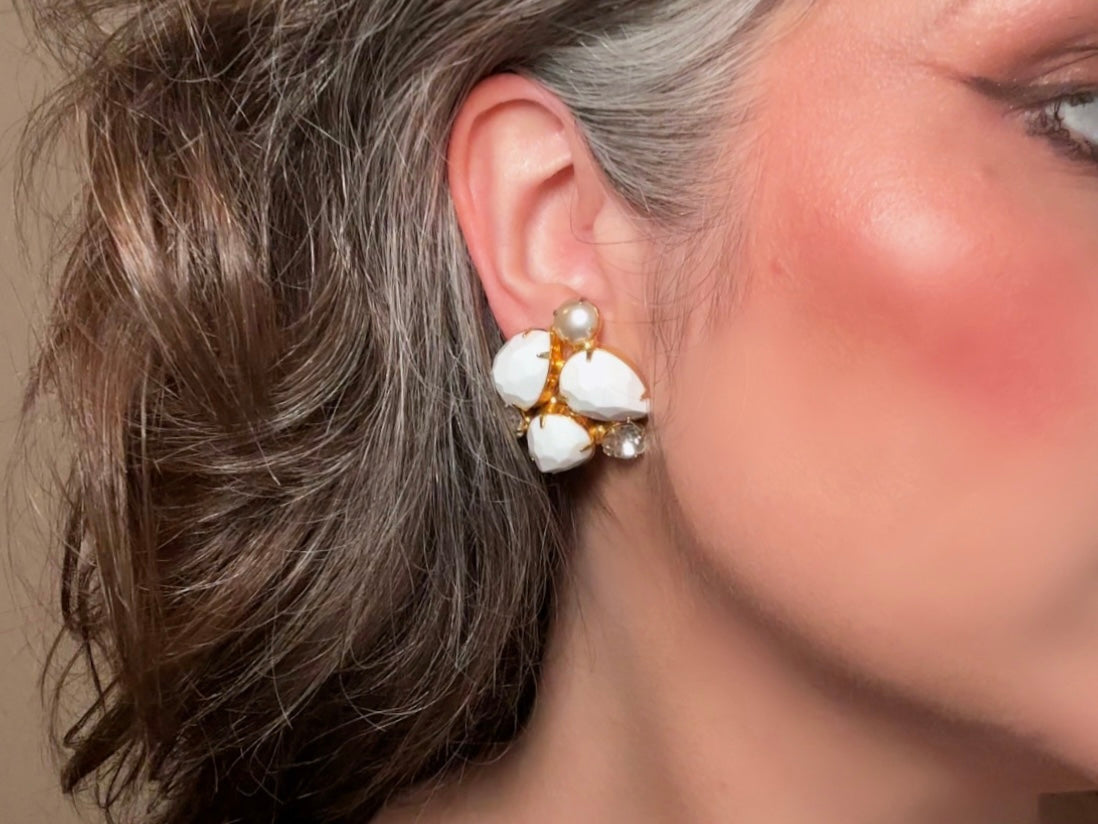 These vintage white earrings are an incredible pair of 1960s cluster earrings. Featuring opaque white faceted pear shaped stones, glass pearls and diamond rhinestones, these gold plated clip on earrings are fantastic. Each stone is prong set in a geometric pattern that mirrors each earring. A show-stopping rare pair of vintage earrings for a cocktail reception, award ceremony or wedding. Excellent vintage condition, please view all pics.