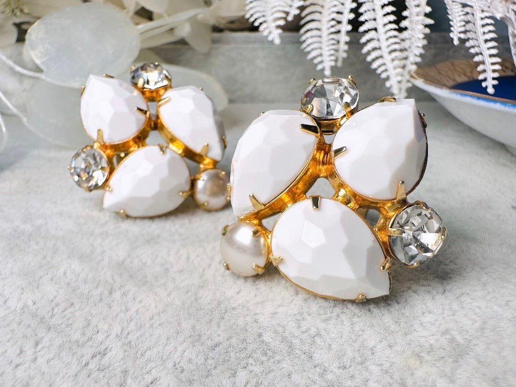 These vintage white earrings are an incredible pair of 1960s cluster earrings. Featuring opaque white faceted pear shaped stones, glass pearls and diamond rhinestones, these gold plated clip on earrings are fantastic. Each stone is prong set in a geometric pattern that mirrors each earring. A show-stopping rare pair of vintage earrings for a cocktail reception, award ceremony or wedding. Excellent vintage condition, please view all pics.