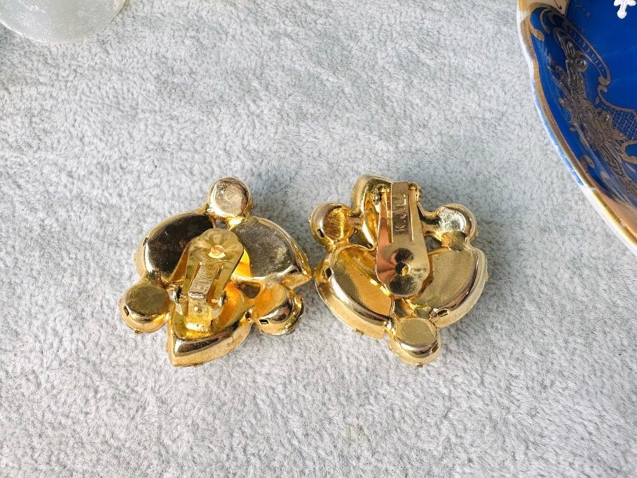 These vintage white earrings are an incredible pair of 1960s cluster earrings. Featuring opaque white faceted pear shaped stones, glass pearls and diamond rhinestones, these gold plated clip on earrings are fantastic. Each stone is prong set in a geometric pattern that mirrors each earring. A show-stopping rare pair of vintage earrings for a cocktail reception, award ceremony or wedding. Excellent vintage condition, please view all pics.
