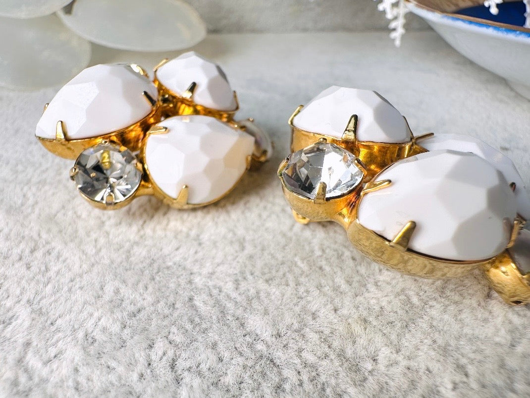These vintage white earrings are an incredible pair of 1960s cluster earrings. Featuring opaque white faceted pear shaped stones, glass pearls and diamond rhinestones, these gold plated clip on earrings are fantastic. Each stone is prong set in a geometric pattern that mirrors each earring. A show-stopping rare pair of vintage earrings for a cocktail reception, award ceremony or wedding. Excellent vintage condition, please view all pics.