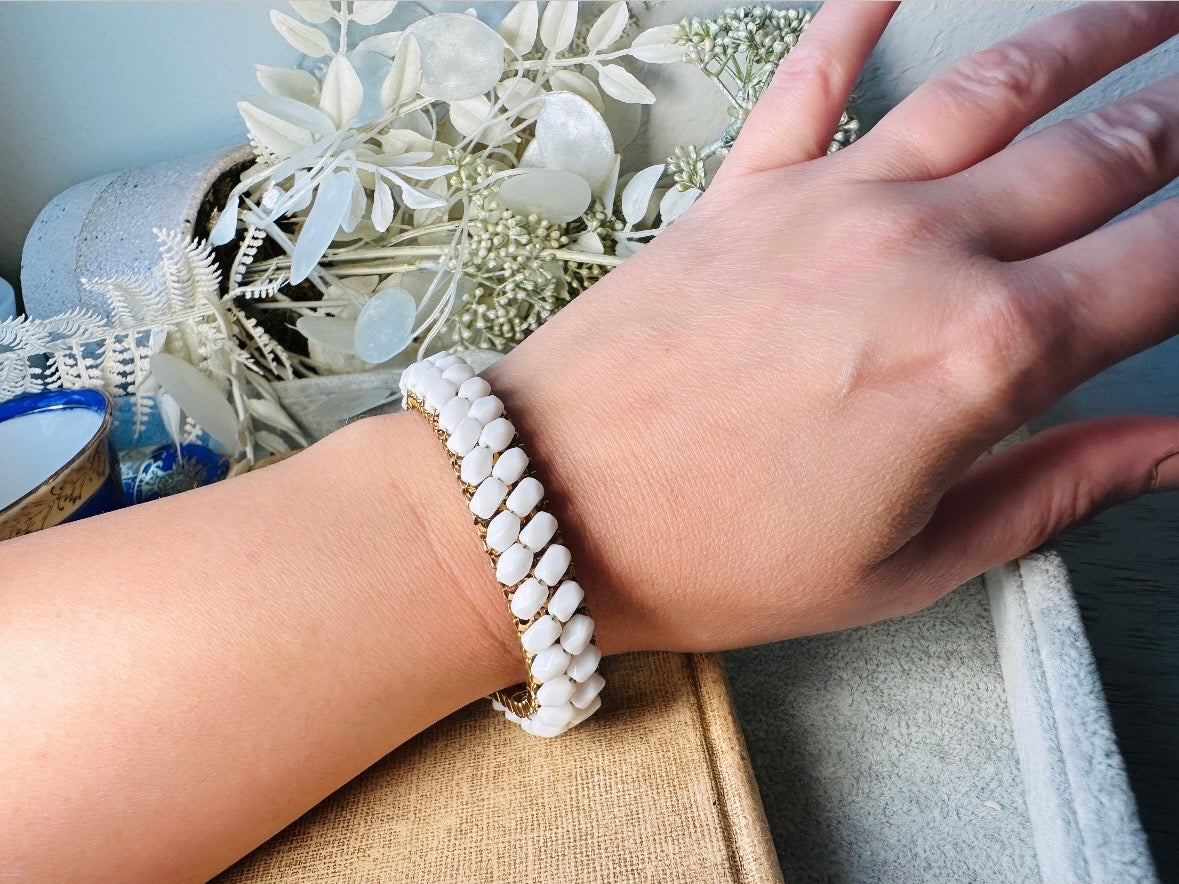 This beautiful white and gold 1960s vintage bracelet is so very pretty. Featuring triple strands of gold mesh chain with two strands of faceted milk glass crystals woven into the design. A simple spring ring closure brings this bracelet together. Easy to wear for everyday or would make a gorgeous bridal piece. A classic 1960s piece- in great vintage condition- &nbsp;please see all pics.

Dimensions: approximately 7.5" long, 0.5" wide.