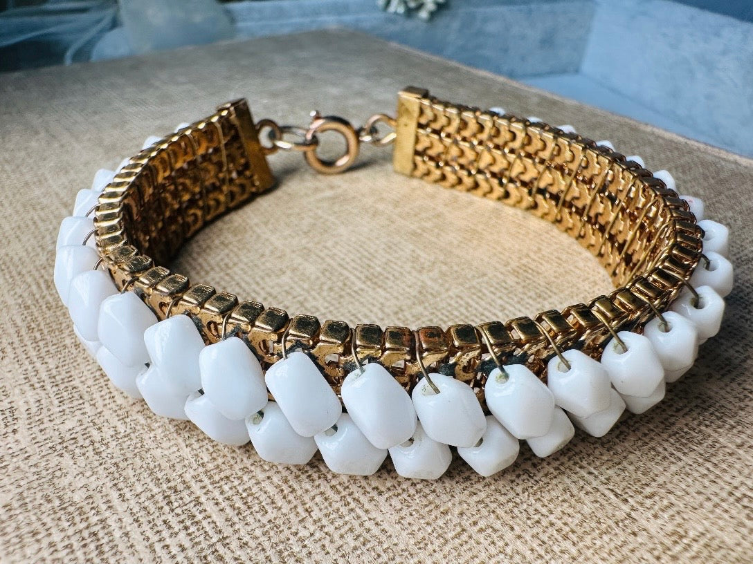 This beautiful white and gold 1960s vintage bracelet is so very pretty. Featuring triple strands of gold mesh chain with two strands of faceted milk glass crystals woven into the design. A simple spring ring closure brings this bracelet together. Easy to wear for everyday or would make a gorgeous bridal piece. A classic 1960s piece- in great vintage condition- &nbsp;please see all pics.

Dimensions: approximately 7.5" long, 0.5" wide.