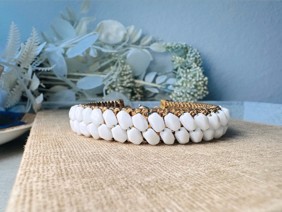 This beautiful white and gold 1960s vintage bracelet is so very pretty. Featuring triple strands of gold mesh chain with two strands of faceted milk glass crystals woven into the design. A simple spring ring closure brings this bracelet together. Easy to wear for everyday or would make a gorgeous bridal piece. A classic 1960s piece- in great vintage condition- &nbsp;please see all pics.

Dimensions: approximately 7.5" long, 0.5" wide.