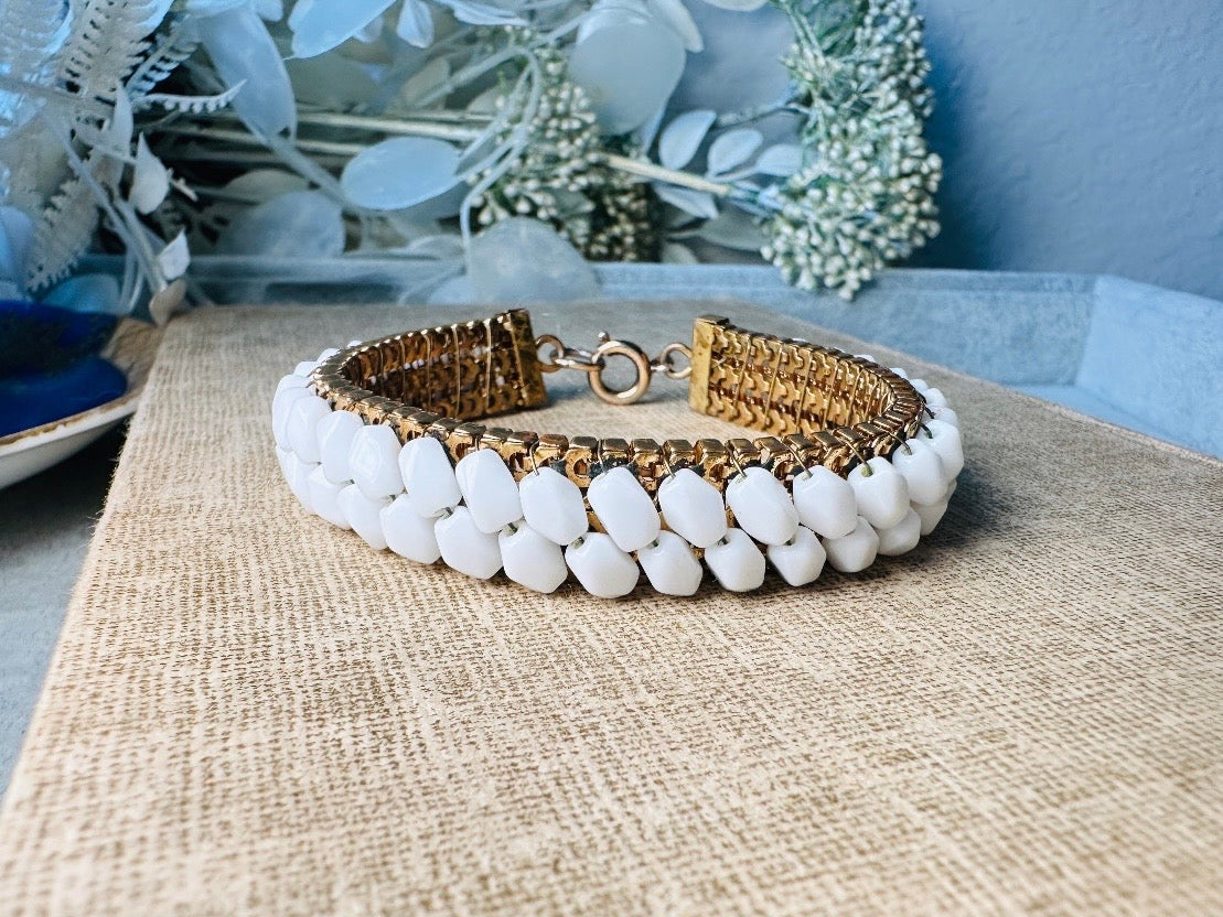This beautiful white and gold 1960s vintage bracelet is so very pretty. Featuring triple strands of gold mesh chain with two strands of faceted milk glass crystals woven into the design. A simple spring ring closure brings this bracelet together. Easy to wear for everyday or would make a gorgeous bridal piece. A classic 1960s piece- in great vintage condition- &nbsp;please see all pics.

Dimensions: approximately 7.5" long, 0.5" wide.