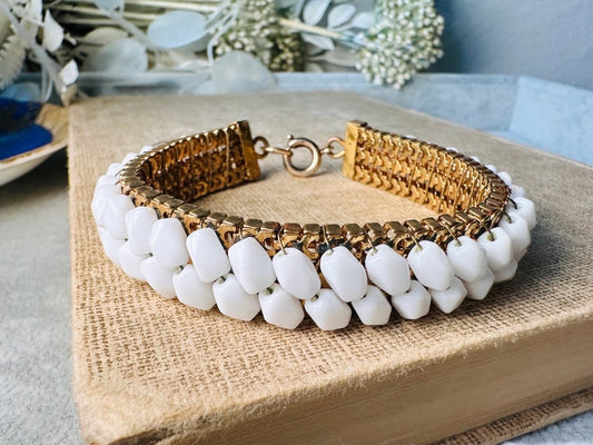 This beautiful white and gold 1960s vintage bracelet is so very pretty. Featuring triple strands of gold mesh chain with two strands of faceted milk glass crystals woven into the design. A simple spring ring closure brings this bracelet together. Easy to wear for everyday or would make a gorgeous bridal piece. A classic 1960s piece- in great vintage condition- &nbsp;please see all pics.

Dimensions: approximately 7.5" long, 0.5" wide.