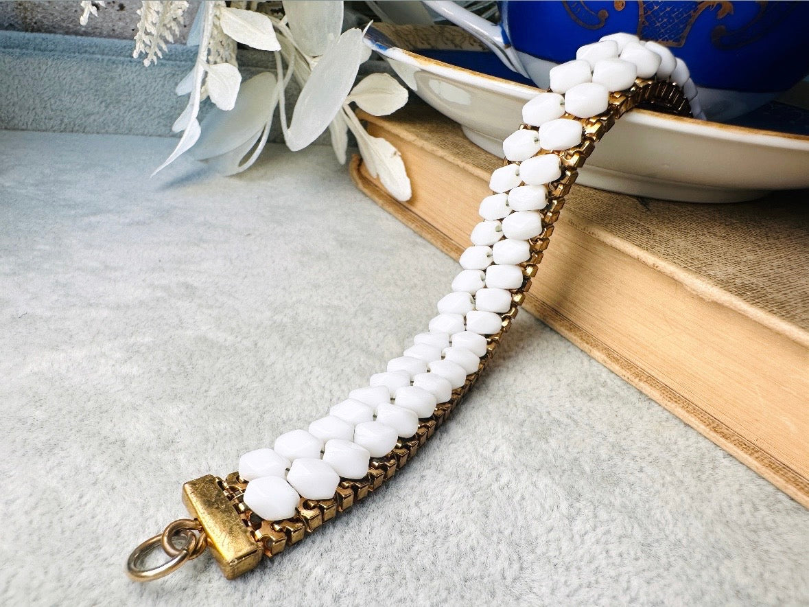 This beautiful white and gold 1960s vintage bracelet is so very pretty. Featuring triple strands of gold mesh chain with two strands of faceted milk glass crystals woven into the design. A simple spring ring closure brings this bracelet together. Easy to wear for everyday or would make a gorgeous bridal piece. A classic 1960s piece- in great vintage condition- &nbsp;please see all pics.

Dimensions: approximately 7.5" long, 0.5" wide.
